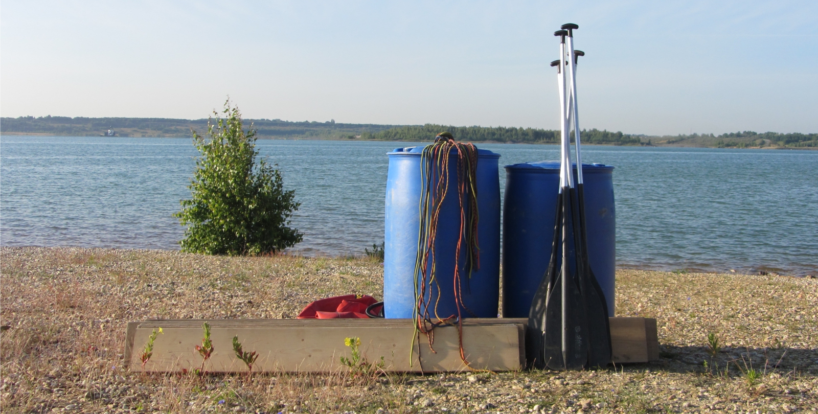 Drei Gruppen padeln auf ihren selbstgebauten Fl��en �ber einen See