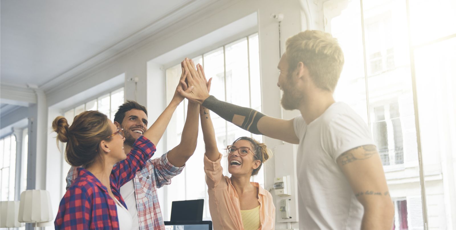 Vier Jugendliche stehen im Halbkreis und geben sich high five