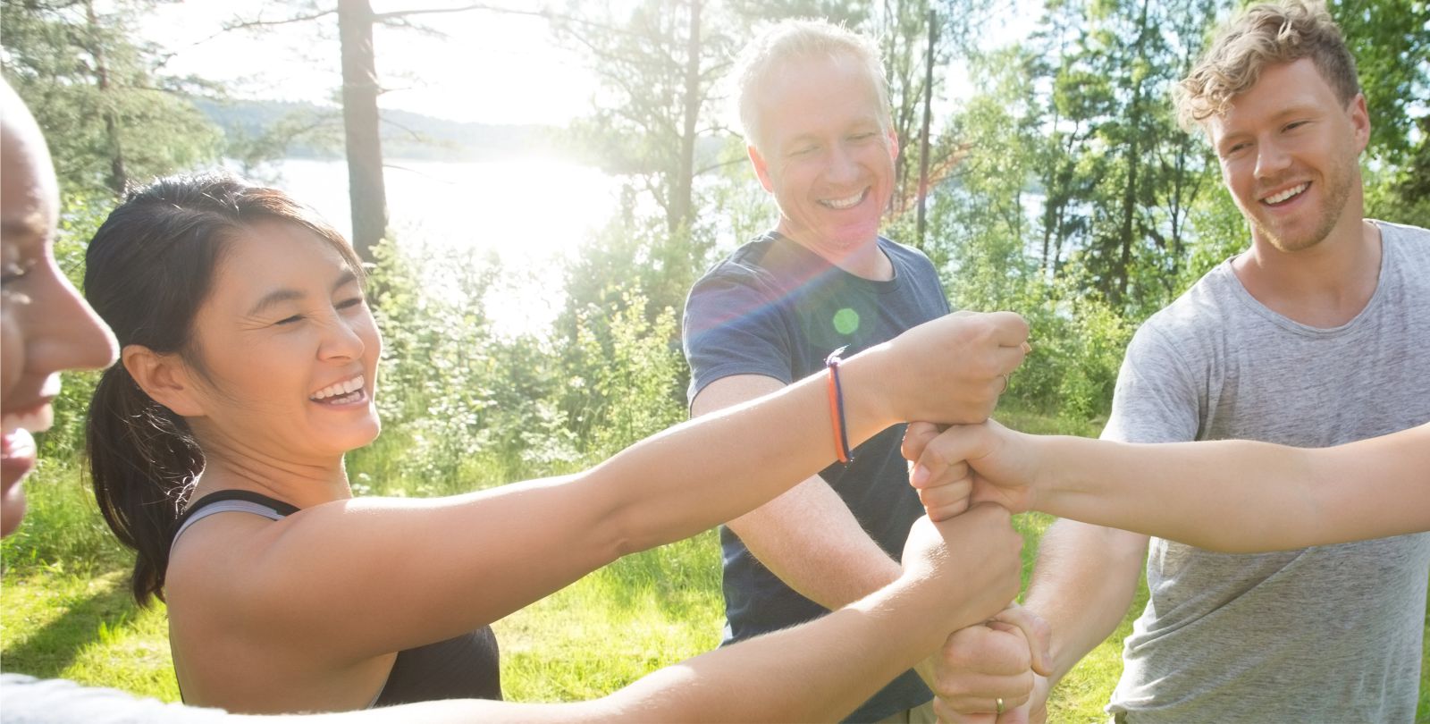 Eine Gruppe Erwachsener steht im Halbkreis und bildet in der Mitte mit Ihren Fusten einen Turm