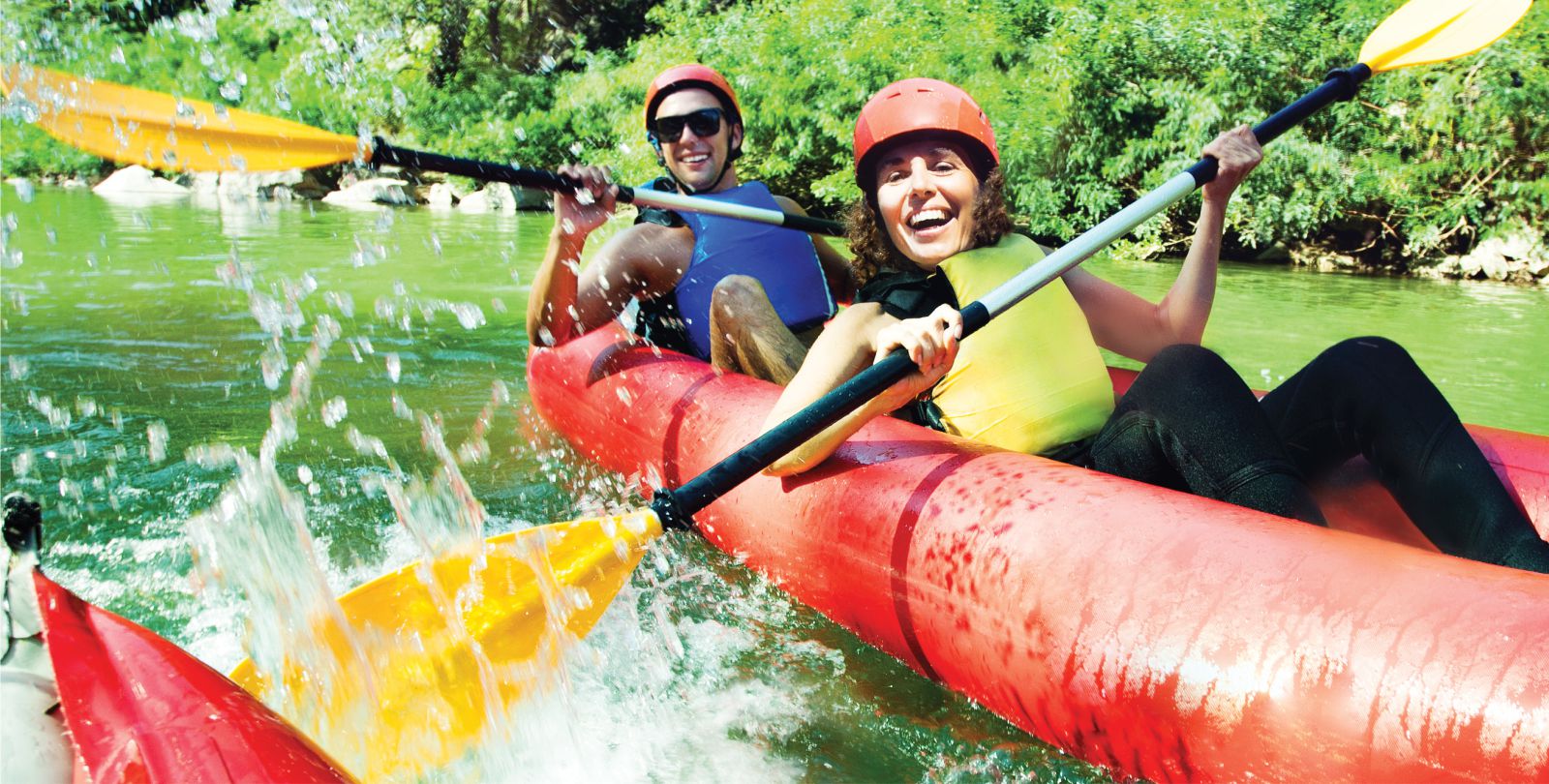Ein Mann und eine Frau in einem Paddelboot lachen in die Kamera