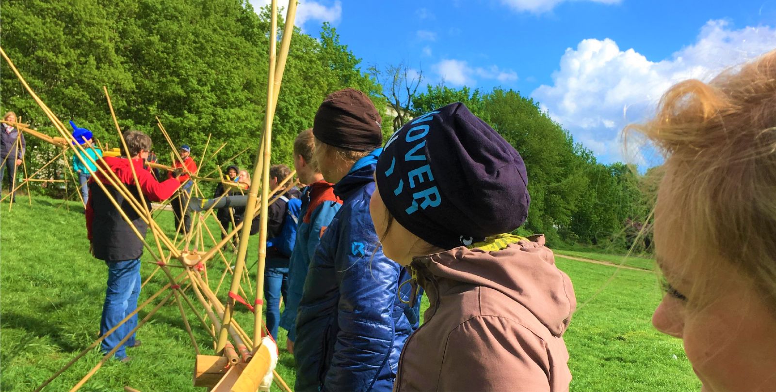 Ein groe Gruppe versucht auf einer Wiese eine Kugelbahn zu bauen