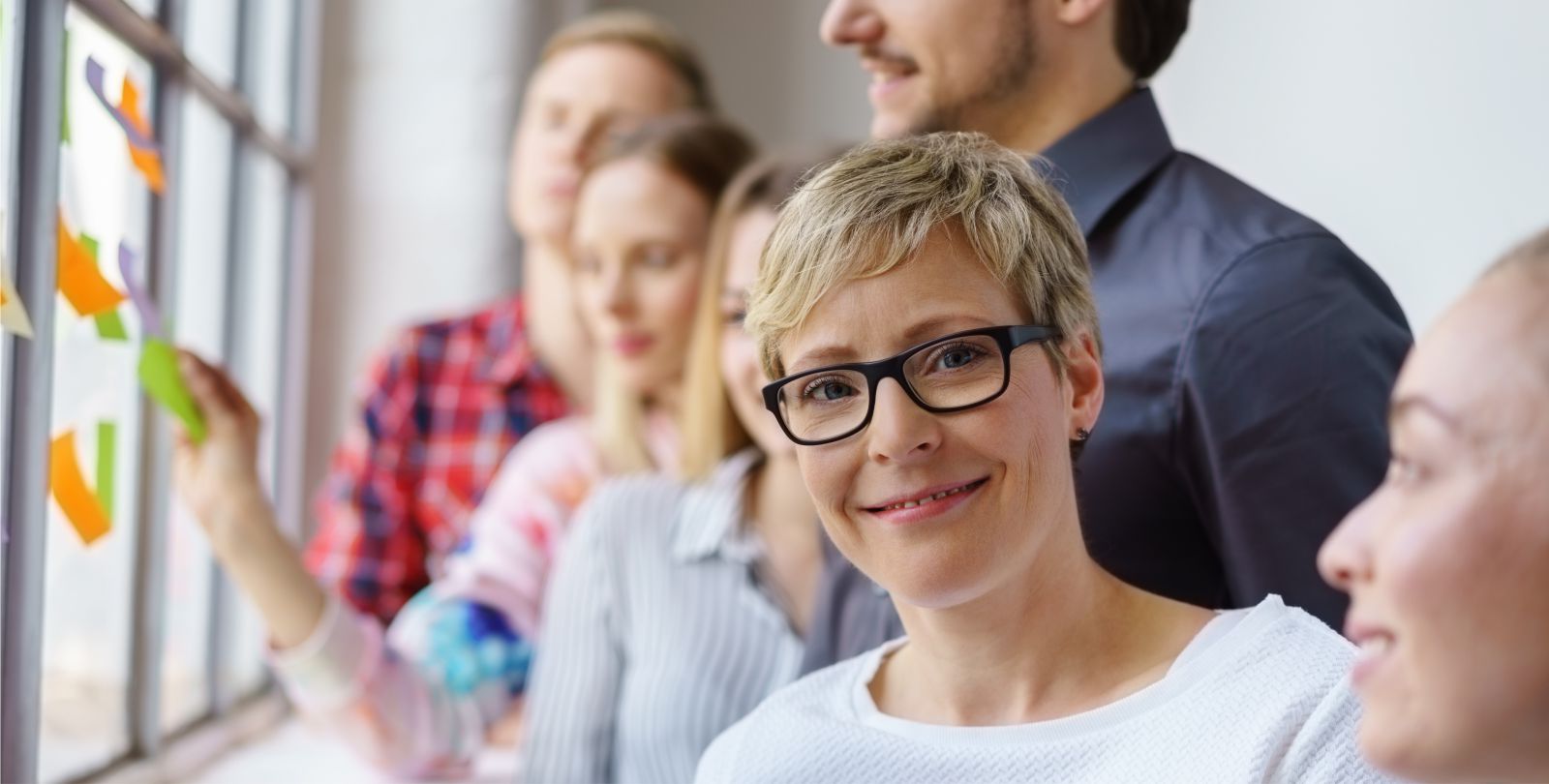 Portrt junge Frau schaut aus einer Gruppe lchelnd in die Kamera