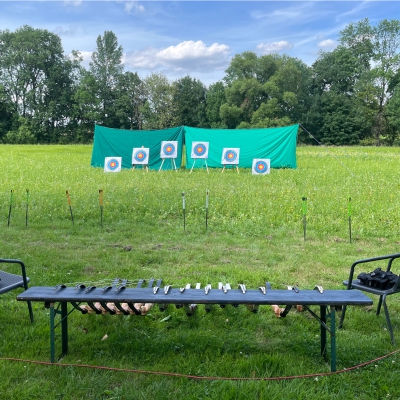 Bogenschie�anlage aufgebaut, vorn ein Tisch mit B�gen, im Hintergrund die Zielscheiben auf einer Wiese
