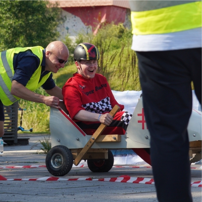 Seifenkistenrennen - jemand schiebt einen Mann mit seiner Seifenkiste an