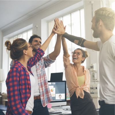 Vier junge Erwachsene stehen zusammen und geben sich lachend high five