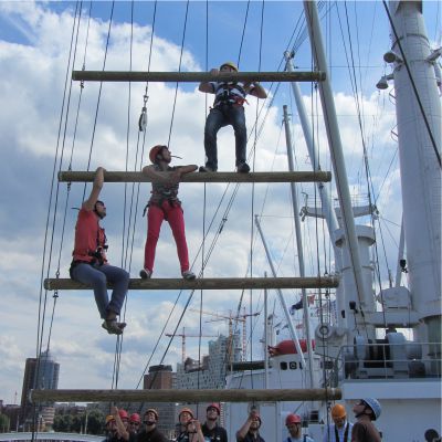 Drei Kletterer versuchen gemeinsam ein Kletterelement auf dem Schiff der Cap San Diego zu bewltigen