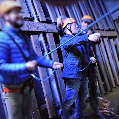 Drei Teilnehmer unter Deck der Cap San Diego bereiten sich aufs Klettern vor