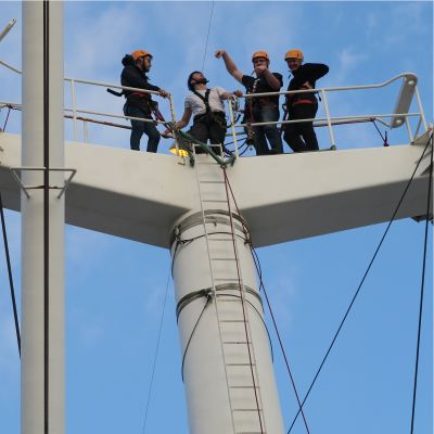 Aufnahme von unten - Vier Kletterer stehen auf einem Mast der Cap San Diego