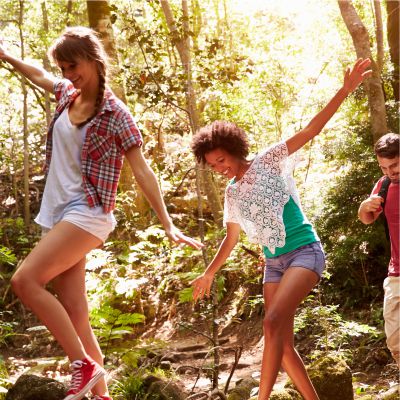 Gruppe Jugendlicher balanciert ber einen Baumstamm