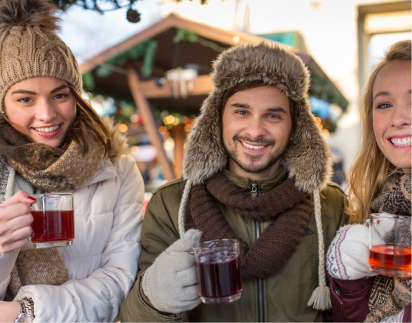 3 junge Menschen auf dem Weihnachtsmarkt beim Gl�hweintrinken