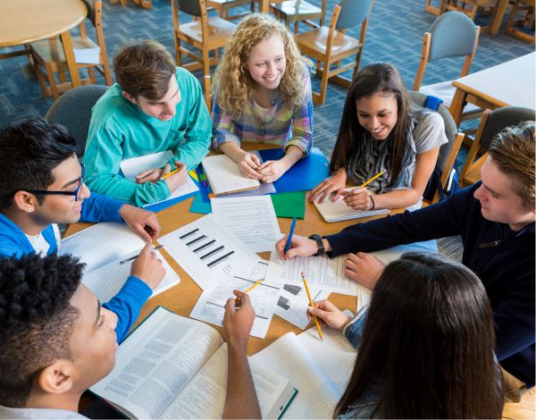 Projektmanagement Training fr Auszubildende - Eine Gruppe Azubis sitzt an einem runden Tisch und bespricht ein gemeinsames Projekt