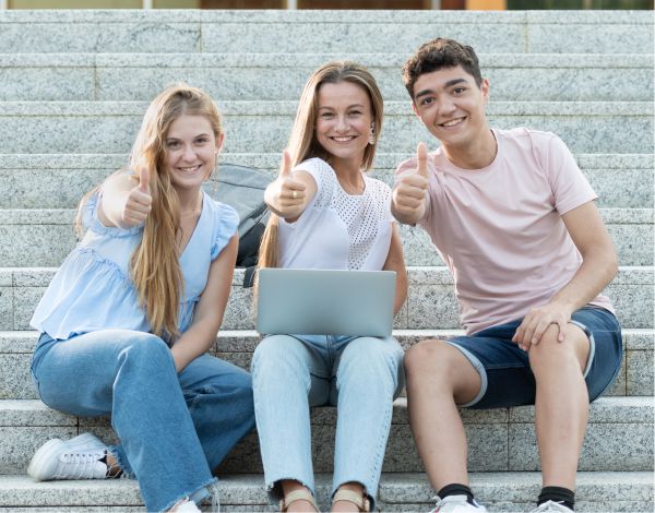 Selbstmanagement Training fr Auszubildende - Drei Jugendliche sitzen auf einer Treppenstufe und recken ihren Daumen freudig in die Kamera