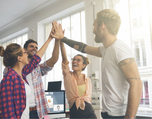 Vier junge Erwachsene klatschen sich lachend ab - high five