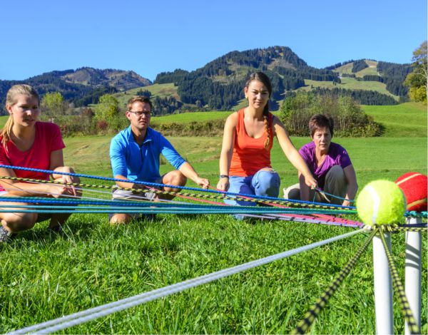 Teamspiel - eine Gruppe versucht gemeinsam Blle mit Schnren zu einem Mittelpunkt zu lenken 