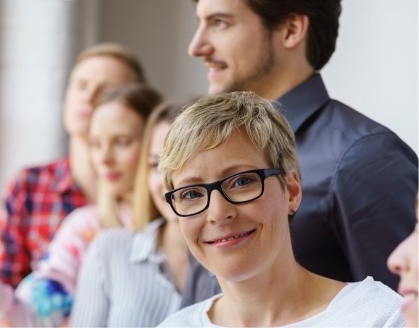 Portrt junge Frau schaut aus einer Gruppe lchelnd in die Kamera